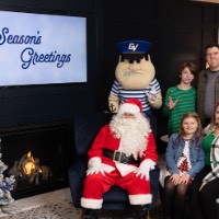 Little girl and mom on chair next to Santa and brother and dad behind chair